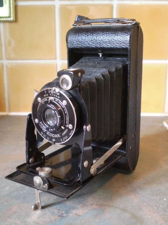 a small antique camera sitting on a tile floor