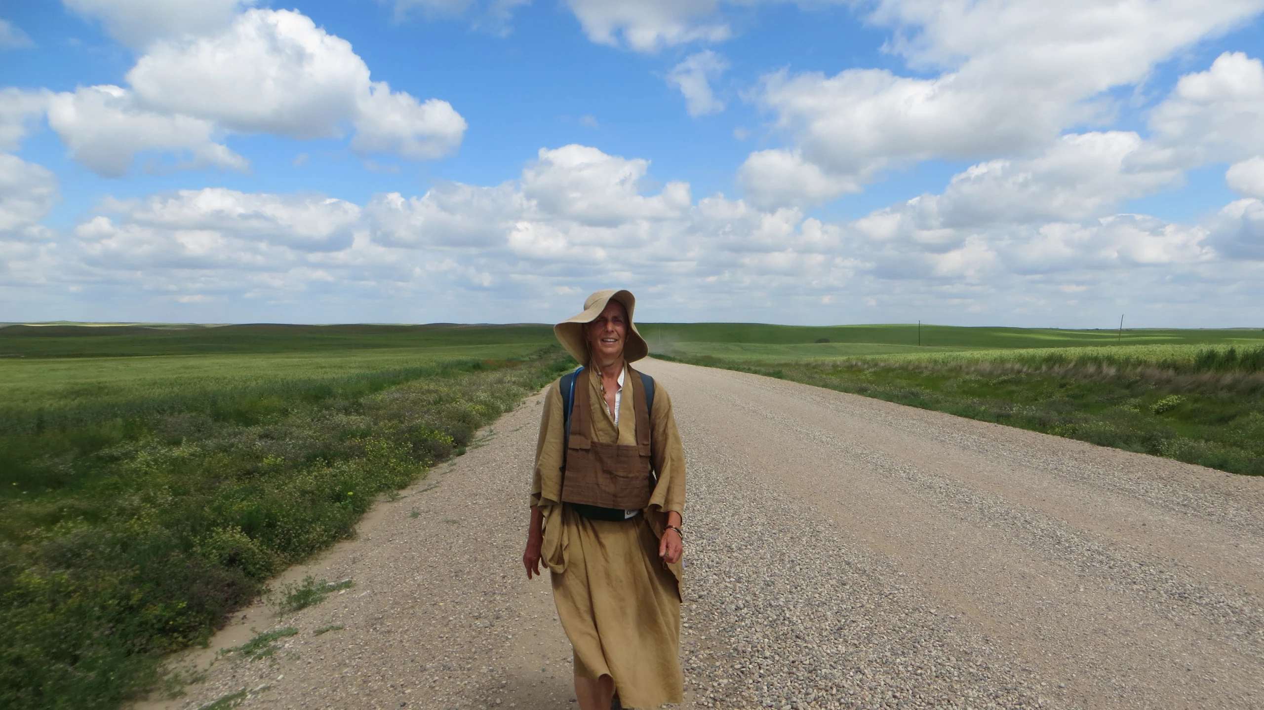 the man with a wide brimmed hat on standing by the dirt road