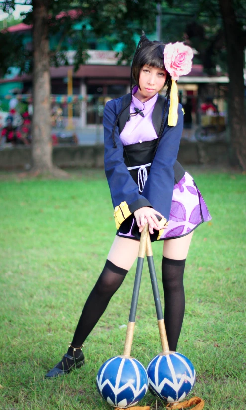 an asian woman standing with two balls and sticks