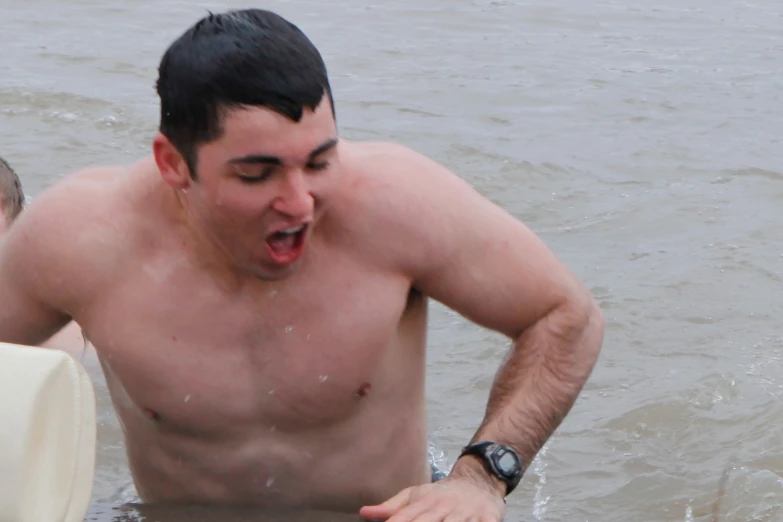 a shirtless man in the water with his mouth open