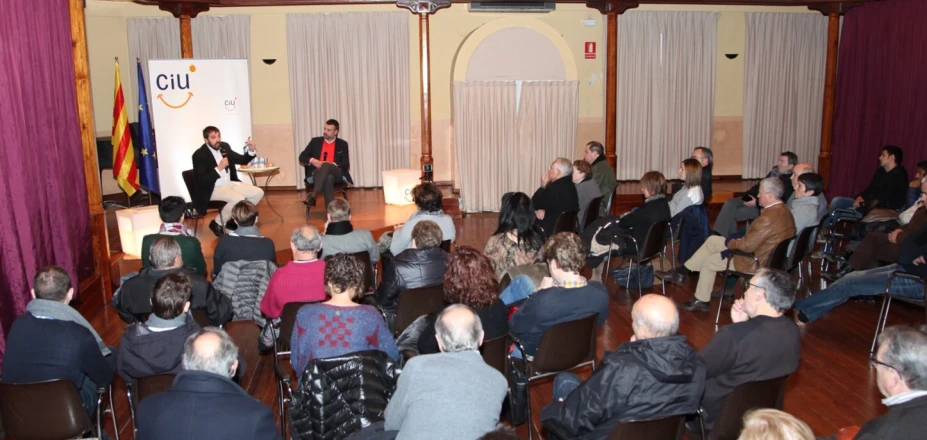 people seated in chairs talking on stage at an event