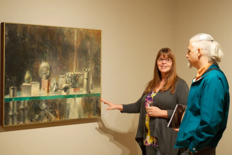 two women pointing at an abstracted painting on display