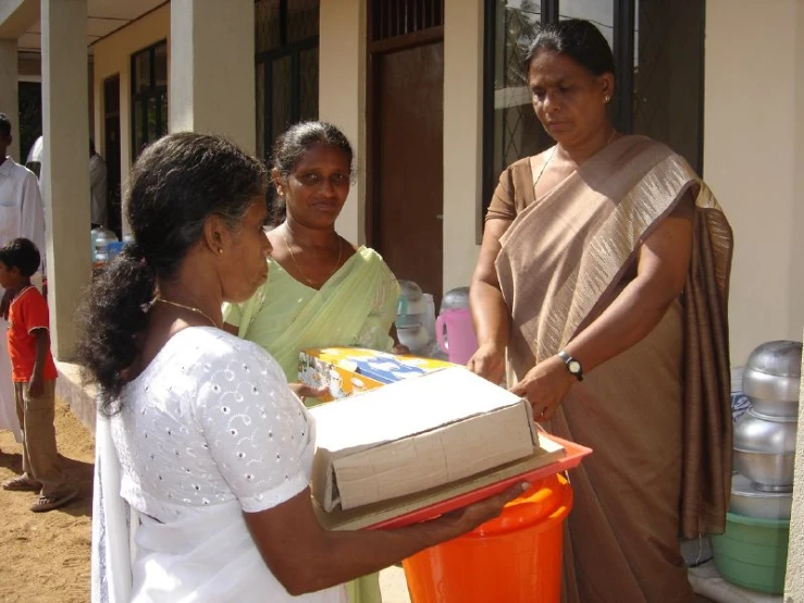 two women are handing out boxes on the street