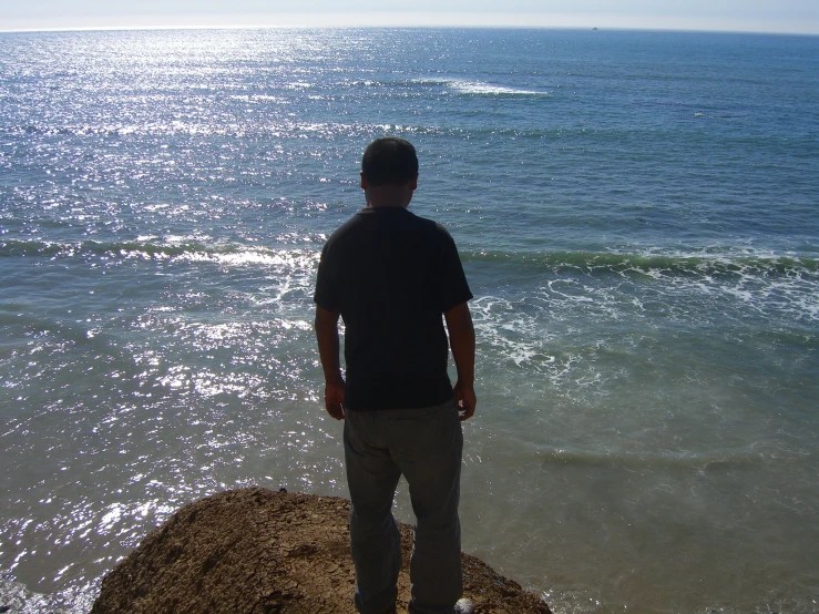 a man standing on a rock near the ocean