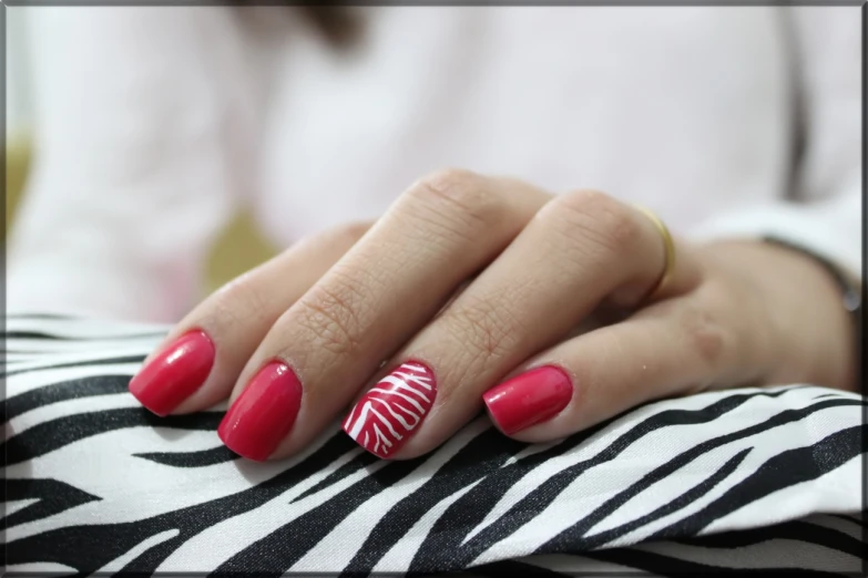 a manicured female with red nails and ze print