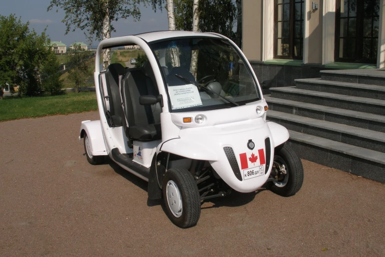 a small white three wheeled vehicle with open doors parked on the side of a road