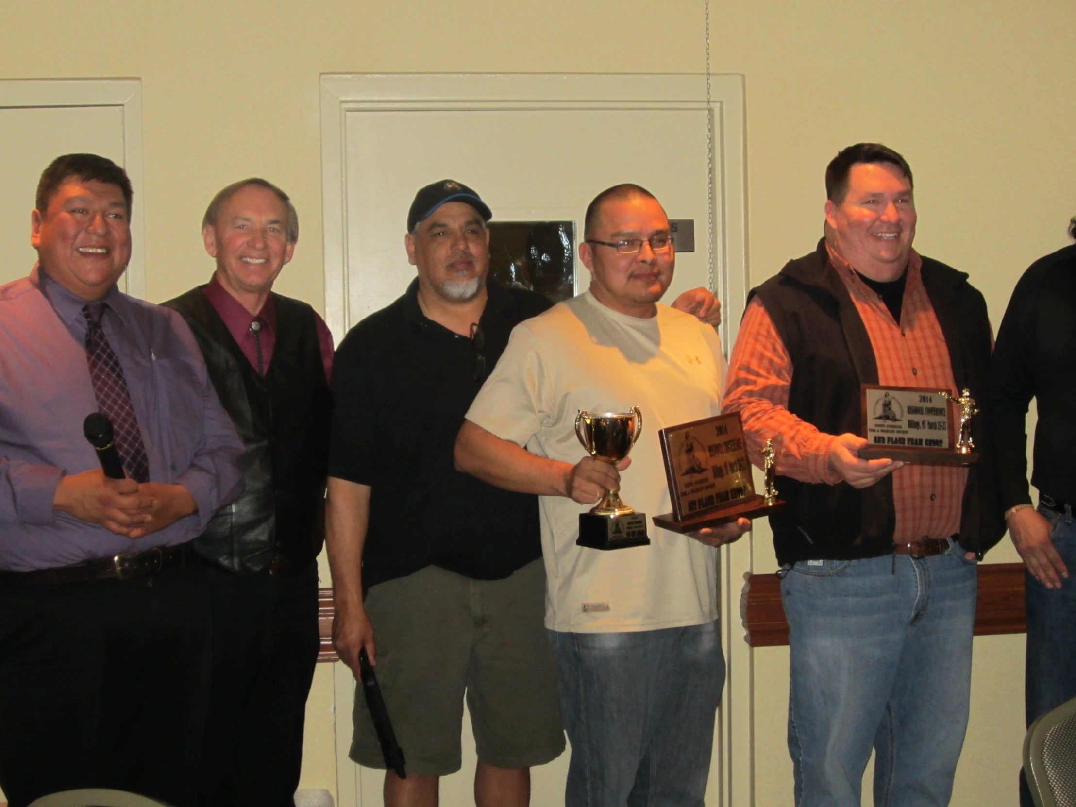 five men holding up small trophies together