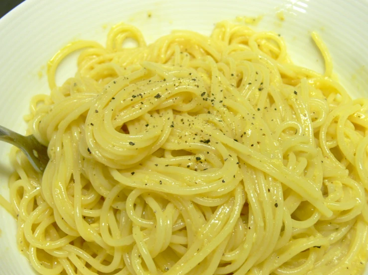 a plate with noodles and mustard sitting on top of a table