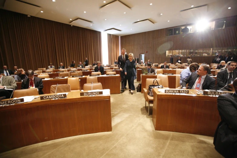 two men in suits stand at the end of a plywood classroom