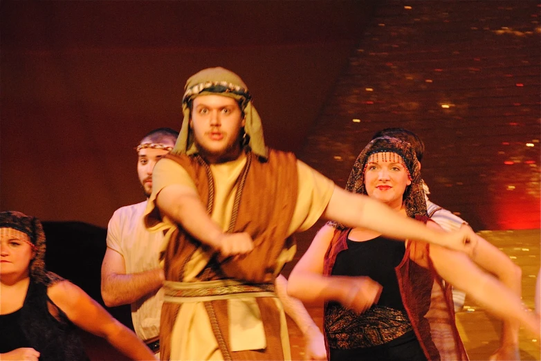 a man with an egyptian dress, dancing while two women watch