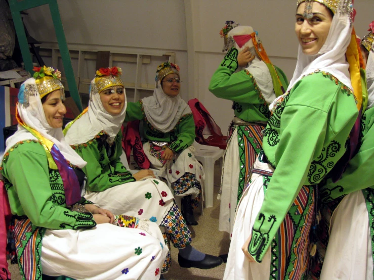 there are many women sitting down wearing their colorful costumes