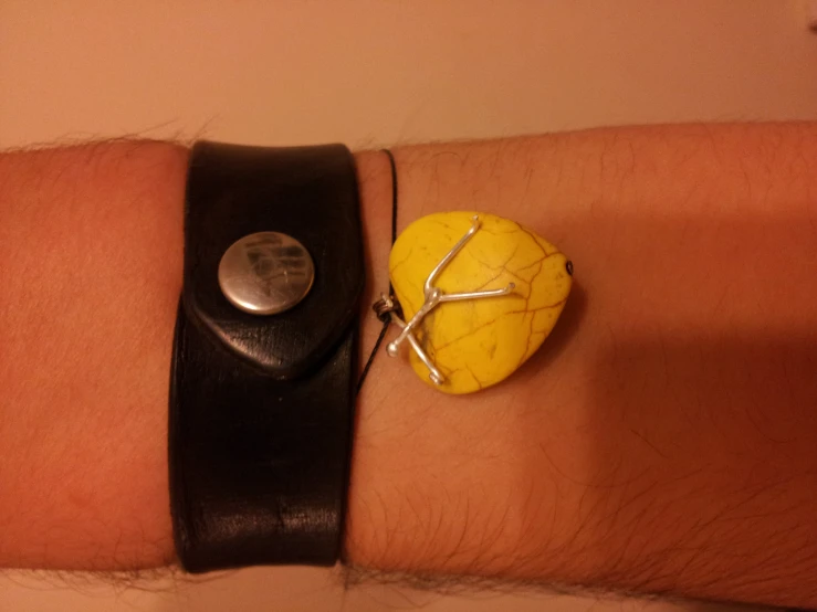 the yellow stone is attached to the black leather strap