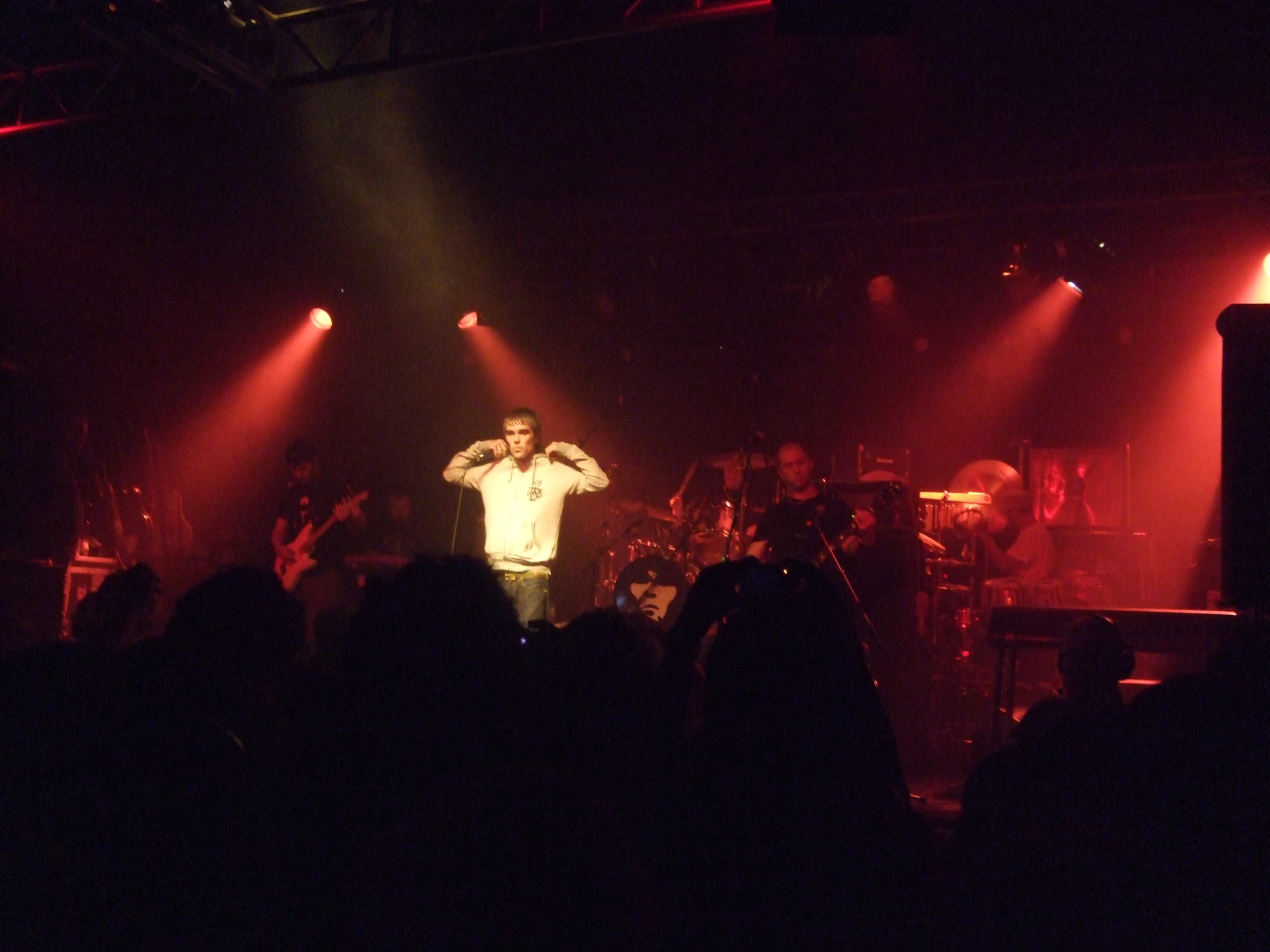 a man on stage holding a microphone in a dark room with some red lighting