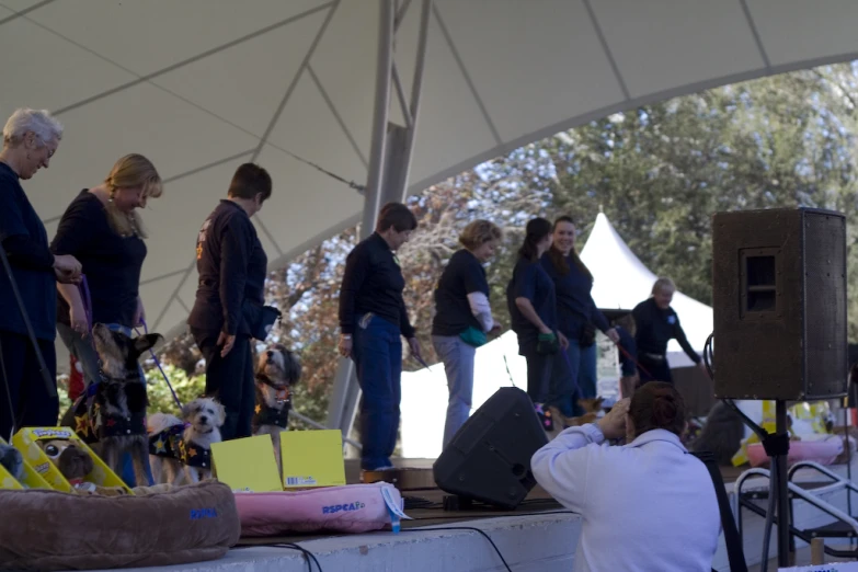 people standing and sitting around near a wall with their bags