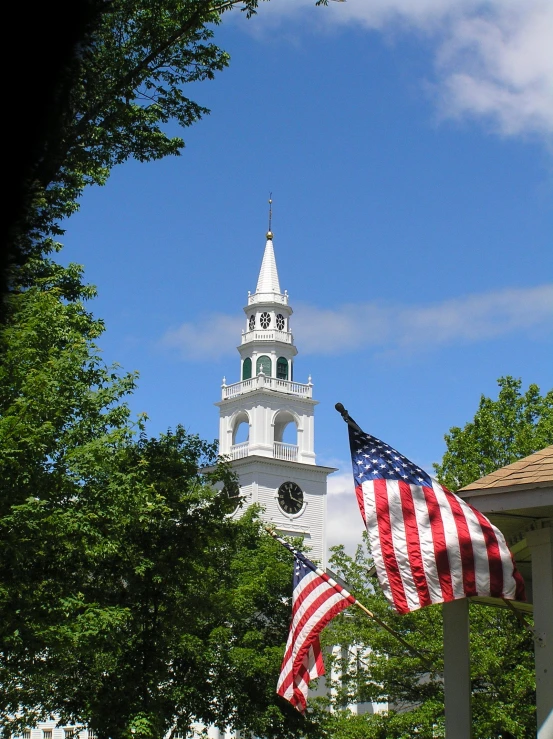 a clock tower with an american flag hanging from it's side