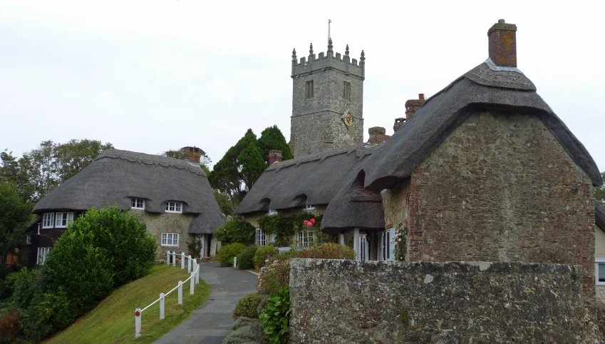 an english village with thatched roofs and stone fences