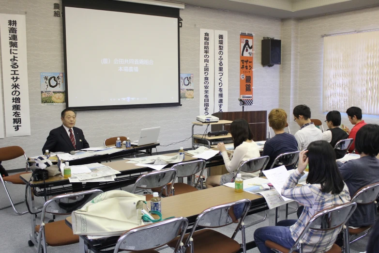 a group of students in a room with chairs and a big screen