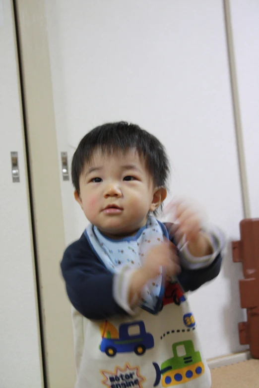 a young asian child standing up with a remote