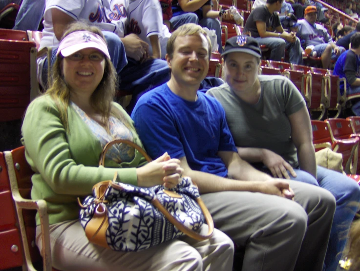 three people sitting in a stadium at the game