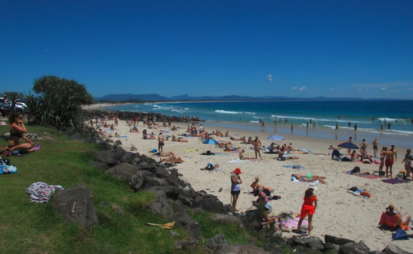 a crowd of people on beach next to the water