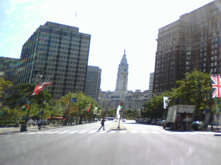 two people crossing an empty city street with buildings in the background