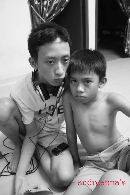 two boys sitting next to each other looking into the camera