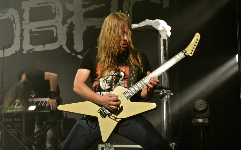 a man holding a white guitar with a yellow pickle in his hand