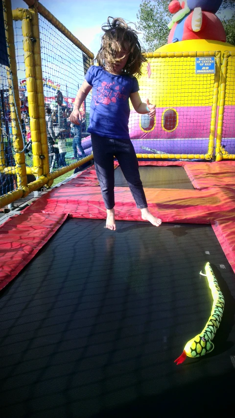 a girl is jumping on a bouncer slide in a children's toy park