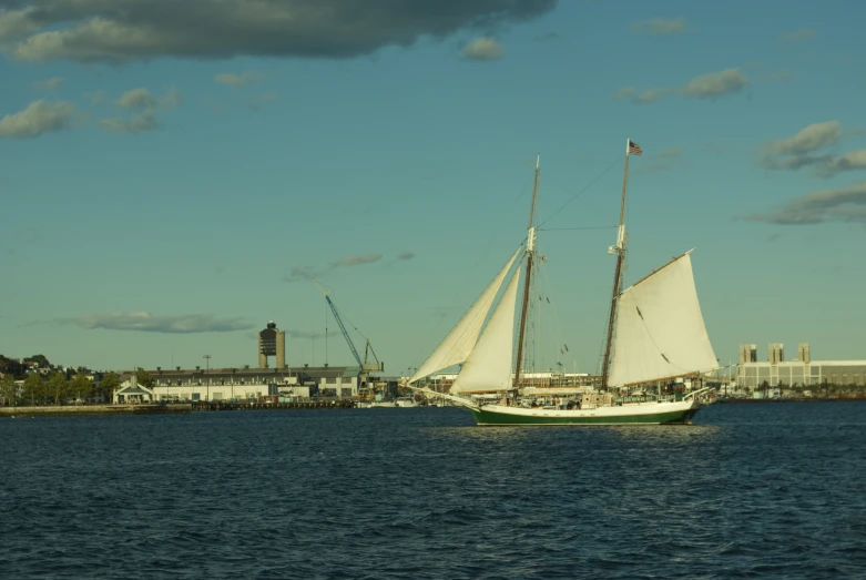 a sail boat sailing down the ocean near a dock