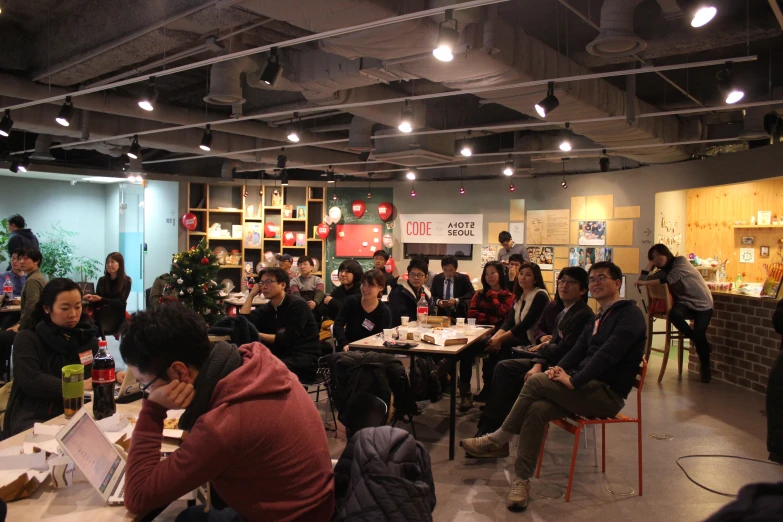 people sit in chairs while others are seated around a small table