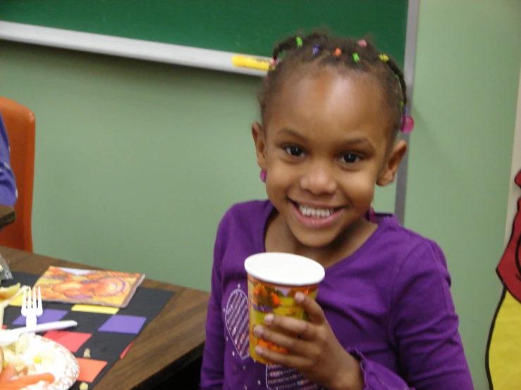 a  holding up a cup next to some food