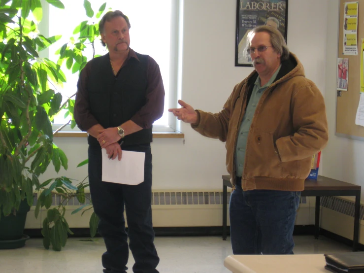 two men standing in front of a tree in an office