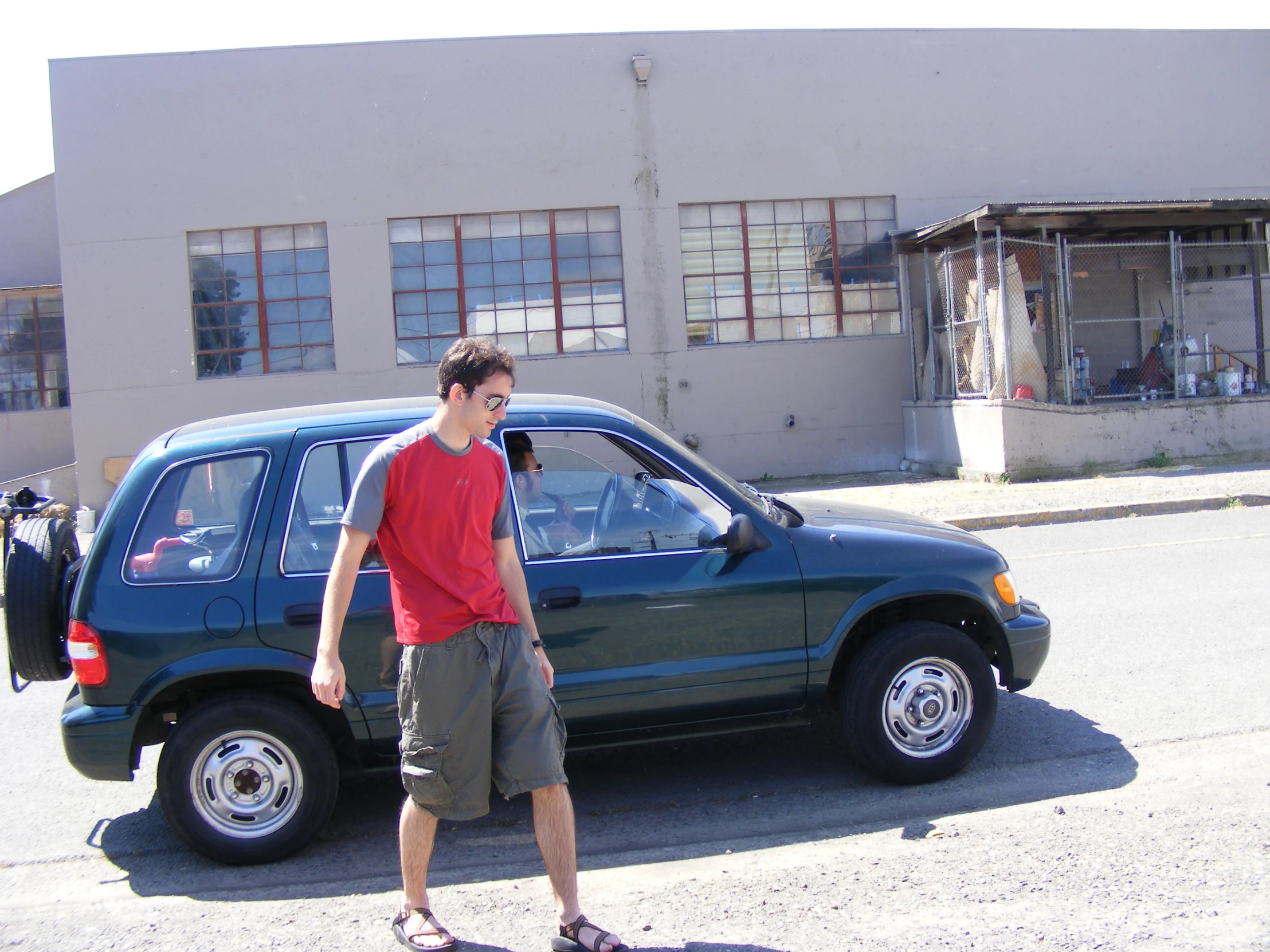 a man walking past a car holding a cellphone