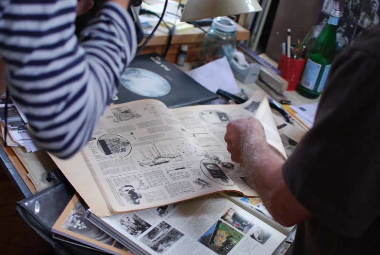 the man is holding up a book with drawings