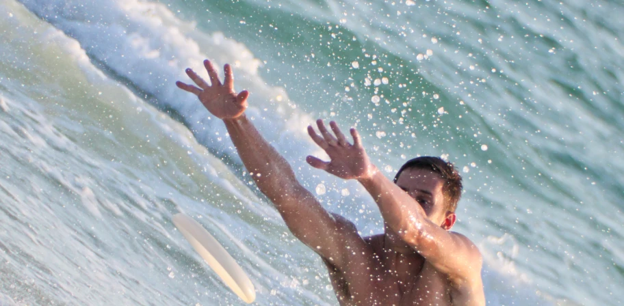 a man standing in the water and reaching for a wave with his hand