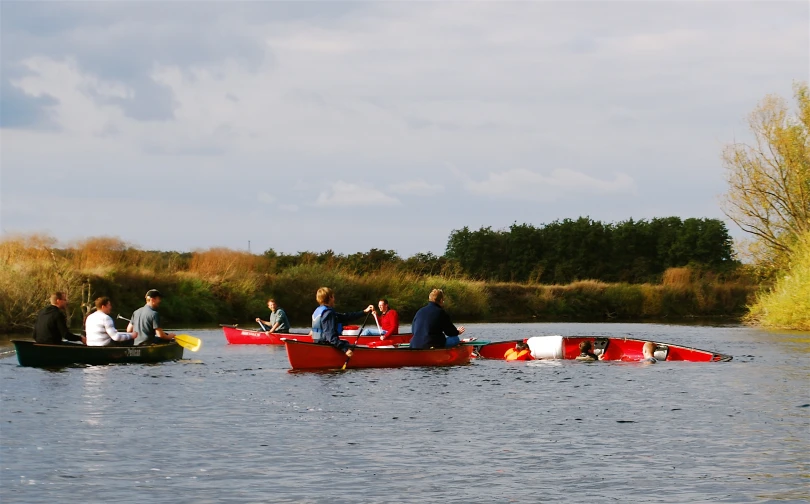 several people rowing canoes along a river in autumn