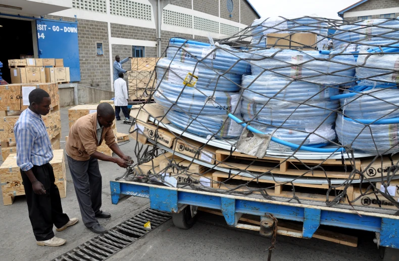 two men loading large cans onto a truck