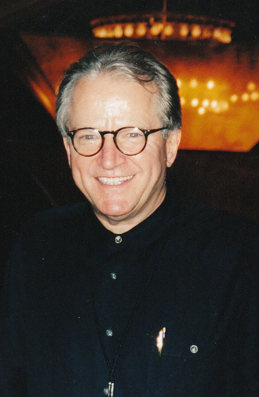 a man wearing glasses smiling at the camera