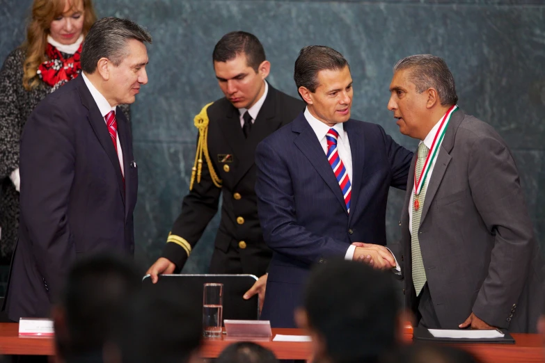 there are several men in suits talking to one another