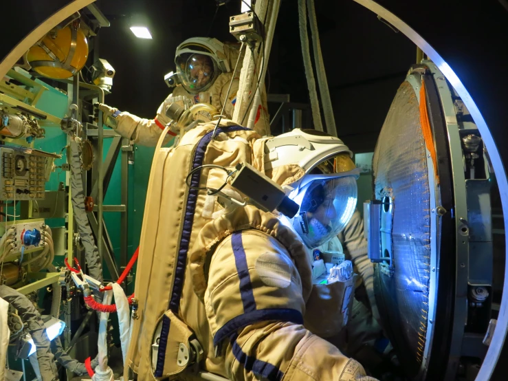 astronaut sitting in space station wearing yellow safety equipment