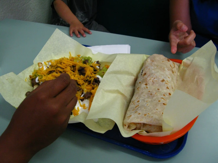 a person is reaching for a burrito that is in a bowl