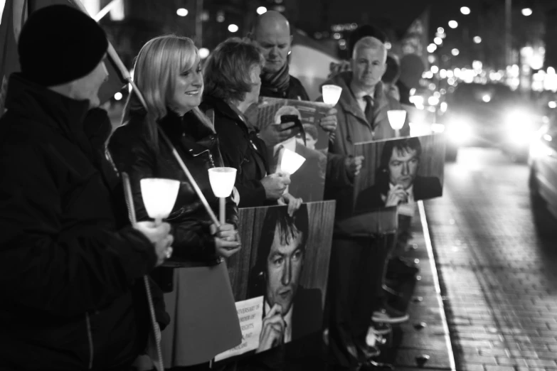 a group of people holding signs and candles on a street