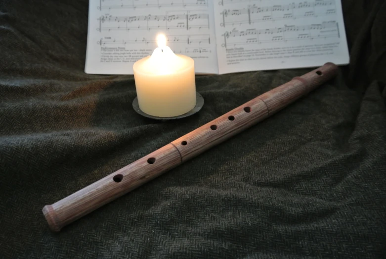 an recorder and candles sit on a bed near the sheet music