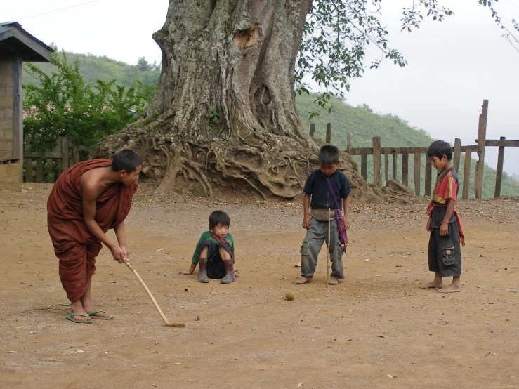 a group of young children playing baseball on a dirt field