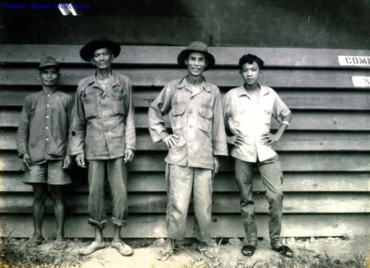 four boys in military uniforms stand by a wall