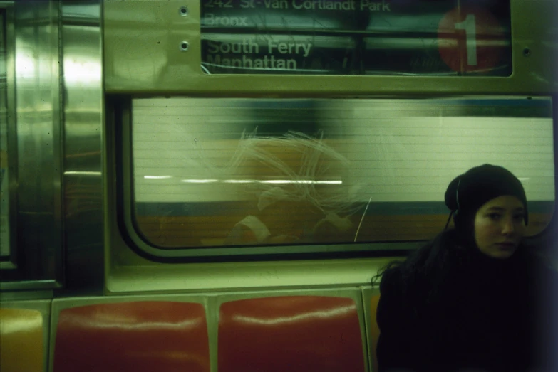 a girl wearing ear phones stands outside a commuter train