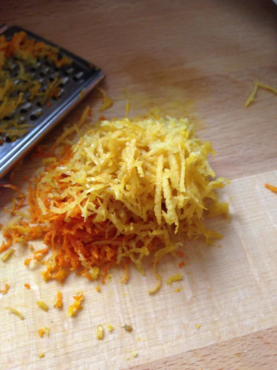 a pile of shredded carrots sitting on a table next to a grater