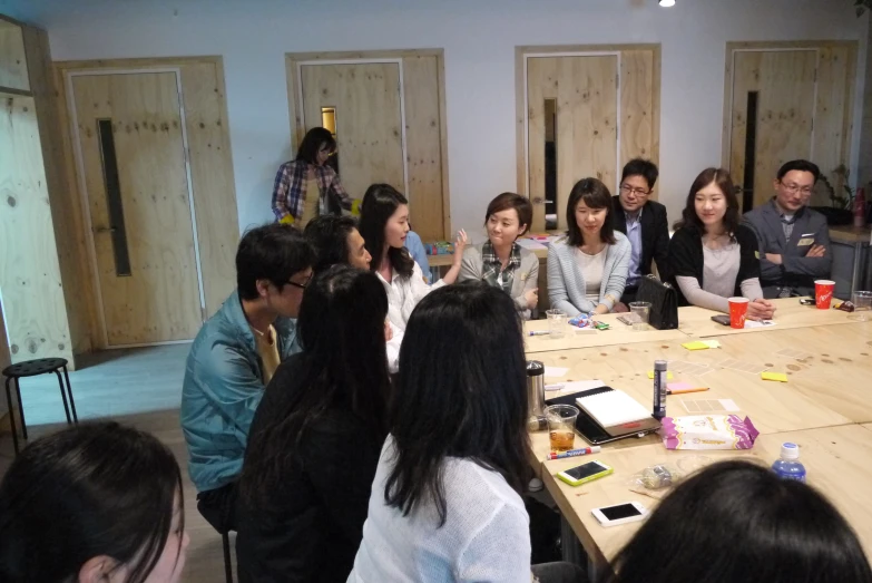 many people are sitting around the large wooden table