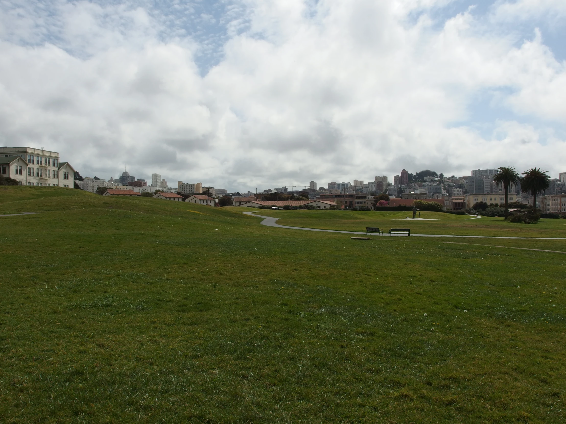 a grassy field with buildings in the background