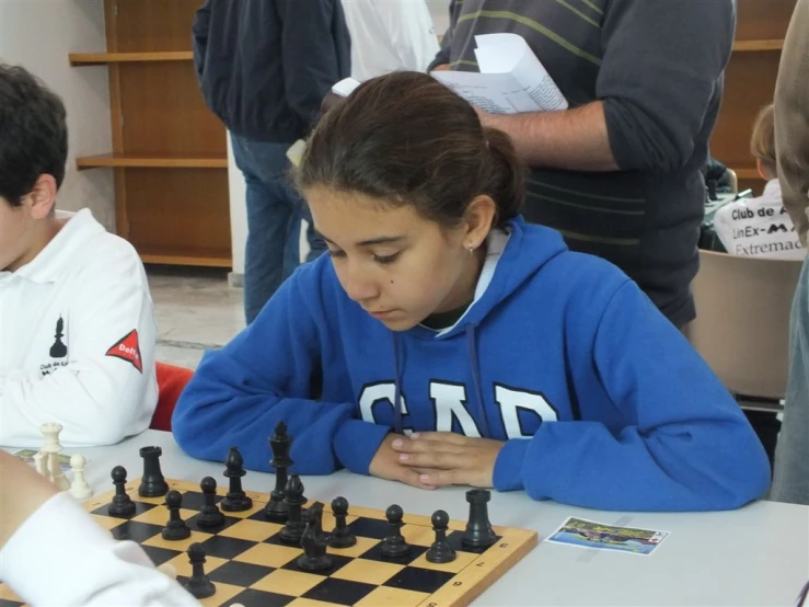 a small child sitting in front of a chess board